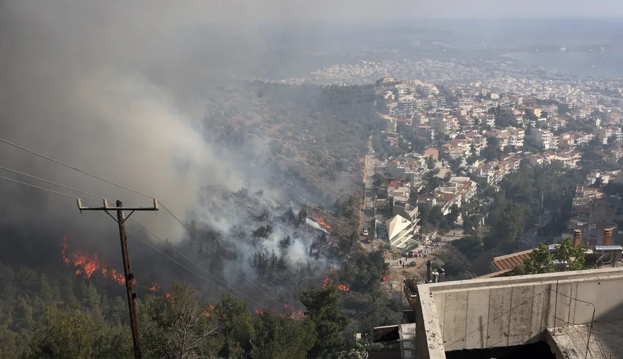 Api membakar pohon di atas bukit saat kebakaran hutan di pinggiran Voula, di selatan Athena, Yunani, Sabtu, 4 Juni 2022. Lebih dari 130 petugas pemadam kebakaran dibantu 6 pesawat pemadam kebakaran dan 4 helikopter menjatuhkan berton-ton air untuk memadamkan api yang telah berkobar selama lebih dari tujuh jam. (AP Photo/Yorgos Karahalis)