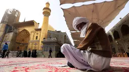 Seorang pria berdoa di luar bangunan masjid makam Imam Ali di kota Najaf, Irak (23/1). Masjid ini merupakan salah satu situs suci bagi penganut Syiah. (AFP Photo/Haidar Hamdani)