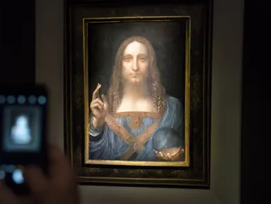 Seorang pengunjung mengambil foto lukisan 'Salvator Mundi' karya Leonardo da Vinci di Christie's New York Auction House, New York City (15/11). Lukisan wajah Yesus Kristus karya da Vinci ini terjual seharga US$ 450,3 juta. (Drew Angerer/Getty Images/AFP)