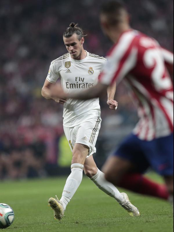 Penyerang Real Madrid, Gareth Bale mengumpan bola saat bertanding melawan Atletico Madrid pada pertandingan lanjutan La Liga di stadion Wanda Metropolitano, Spanyol (28/9/2019). Madrid dan Atletico bermain imbang 0-0. (AP Photo/Bernat Armangue)