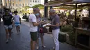 Pemilik restoran memindai kartu kesehatan di sebuah restoran di Marseille, Prancis selatan, Senin (9/8/2021). Prancis mewajibkan semua orang menunjukkan kode QR yang membuktikan mereka memiliki Kartu Vaksinasi untuk memasuki restoran dan kafe atau bepergian di negara tersebut. (AP Photo/Daniel Cole)