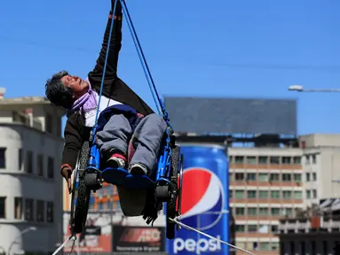 Seorang wanita penyandang cacat menggantungkan diri saat mengelar aksi menuntut kesejahteraan di sebuah jembatan di La Paz, Bolivia (3/5). Aksi ini menuntut pemerintah Bolivia untuk memberikan subsidi bulanan. (REUTERS/David Mercado)