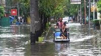 Becak berpenumpang seorang wanita melintasi banjir di kawasan Duta, Jelambar, Jakarta Barat, Selasa (5/3). Sejumlah ruas jalan di Jakarta Barat tergenang air akibat luapan Kali Angke dan drainase yang buruk serta pasang air laut. (merdeka.com/Arie Basuki)