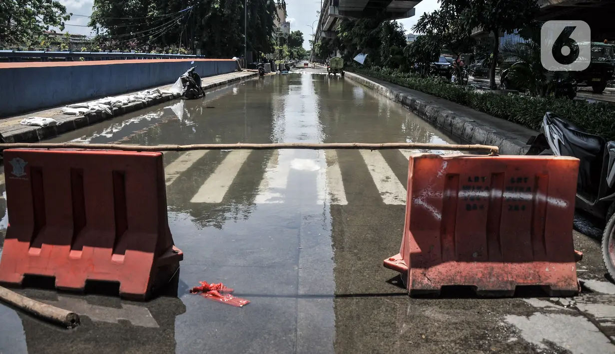 Pembatas jalan dipasang untuk menghalau kendaraan melintasi lokasi banjir di Jalan RE Martadinata, Ancol, Jakarta, Selasa (9/11/2021). Banjir mengakibatkan akses dari arah Jalan Gunung Sahari menuju Penjaringan ditutup sementara dan dialihkan. (merdeka.com/Iqbal S. Nugroho)
