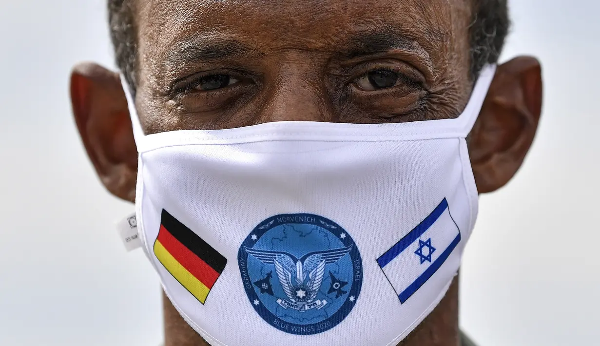Letnan Kolonel Jerman Samuel Mbassa memakai masker dengan bendera Israel dan Jerman di pangkalan udara, Noervenich, Jerman, Kamis (20/8/ 2020. Pilot Israel dan Jerman akan terbang bersama selama dua minggu ke depan selama latihan Angkatan Udara gabungan pertama di Jerman. (AP Photo/Martin Meissner)