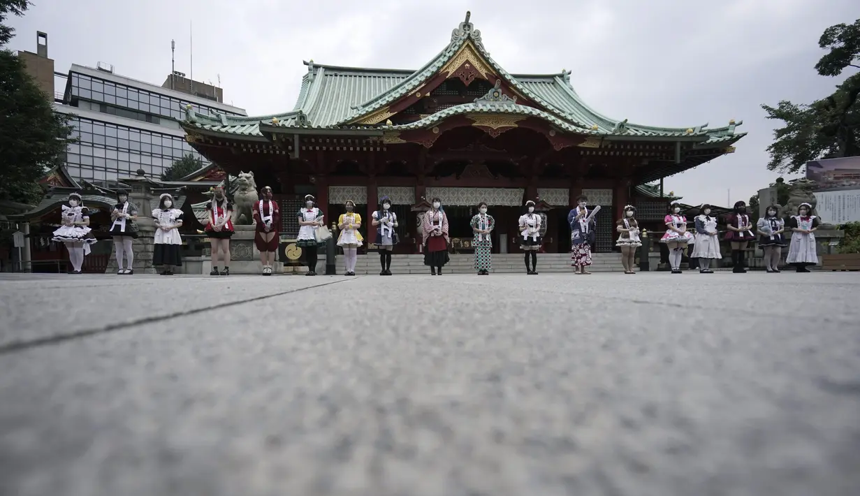 Para karyawan yang mengenakan kostum pelayan dari beberapa kafe bertema pembantu di Akihabara berbaris di kantor polisi sebelum pertemuan doa untuk perlindungan dari COVID-19 dan untuk bisnis yang berkembang di kuil Kanda Myojin, Tokyo (25/7/2020). (AP Photo/Eugene Hoshiko)