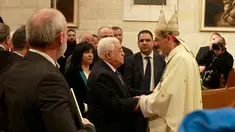 Presiden Palestina Mahmoud Abbas memberikan ucapan selamat Natal pada Uskup Agung Pierbattista Pizzaballa saat misa Natal di Gereja Santa Katarina yang terhubung ke Gereja Nativity, di kota Bethlehem di Tepi Barat, (25/12). (AFP Photo/Musa Shaer Poll)
