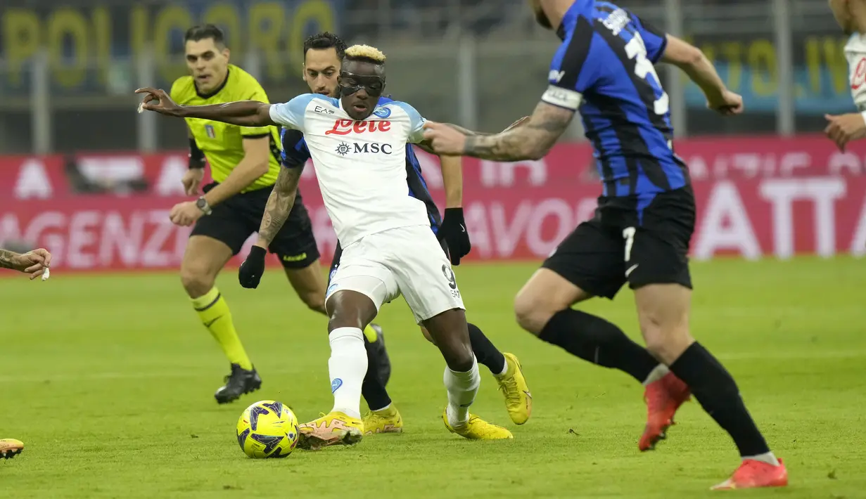 <p>Penyerang Napoli, Victor Osimhen mengumpan bola dari kawalan gelandang Inter Milan, Hakan Calhanoglu pada pertandingan lanjutan Liga Serie A Italia di stadion San Siro di Milan, Italia, Kamis (5/1/2023). Meski kalah, Napoli tetap ada di puncak klasemen sementara dengan 41 poin. (AP Photo/Luca Bruno)</p>