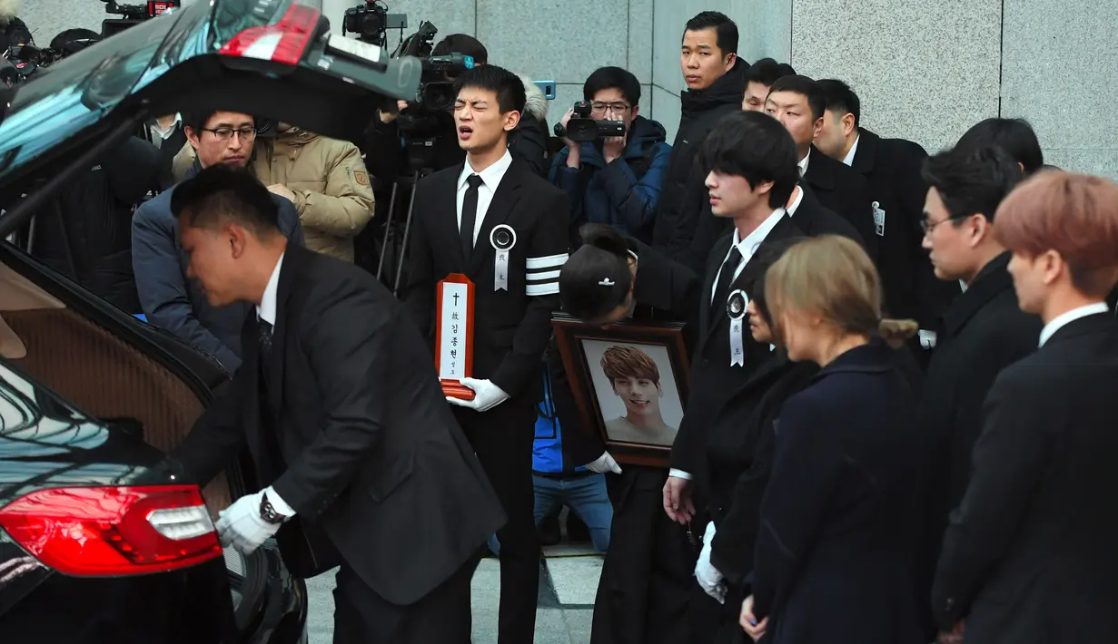 Choi Minho (membawa plakat) berusaha menahan kesedihan saat peti jenazah sang sahabat, Jonghyun SHINee dimasukkan ke mobil menuju tempat pemakaman dari rumah persemayaman di Asan Hospital, Seoul, Kamis (21/12). (JUNG Yeon-Je/AFP)