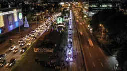 Foto udara kereta wisata yang dihiasi lampu Natal di Bogota (20/12/2019). Meyambut Hari Natal, kereta wisata di Kolombia membuat cara unik dengan memasangkan lampu warna-warni agar menjadi daya tarik penumpang. (AFP Photo/Guillermo Munoz)