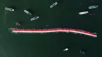 Foto udara memperlihatkan 145 perenang membentangkan bendera Merah Putih sepanjang 78 meter untuk menyambut Hari Ulang Tahun (HUT) ke-78 Republik Indonesia (RI) di perairan Makassar, Sulawesi Selatan, Sabtu (12/8/2023). (Muchtamir ZAIDE/AFP)