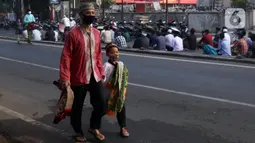 Seorang pria dan seorang anak berjalan saat umat muslim melaksanakan salat Idul Adha 1442 H di Masjid Masjid Jami Al-Mubarok, Tangerang, Banten, Selasa (20/7/2021). Sebagian masjid melakukan pelaksanaan salat Idul Adha 1442 H, namun dengan protokol kesehatan yang ketat. (Liputan6.com/Angga Yuniar)