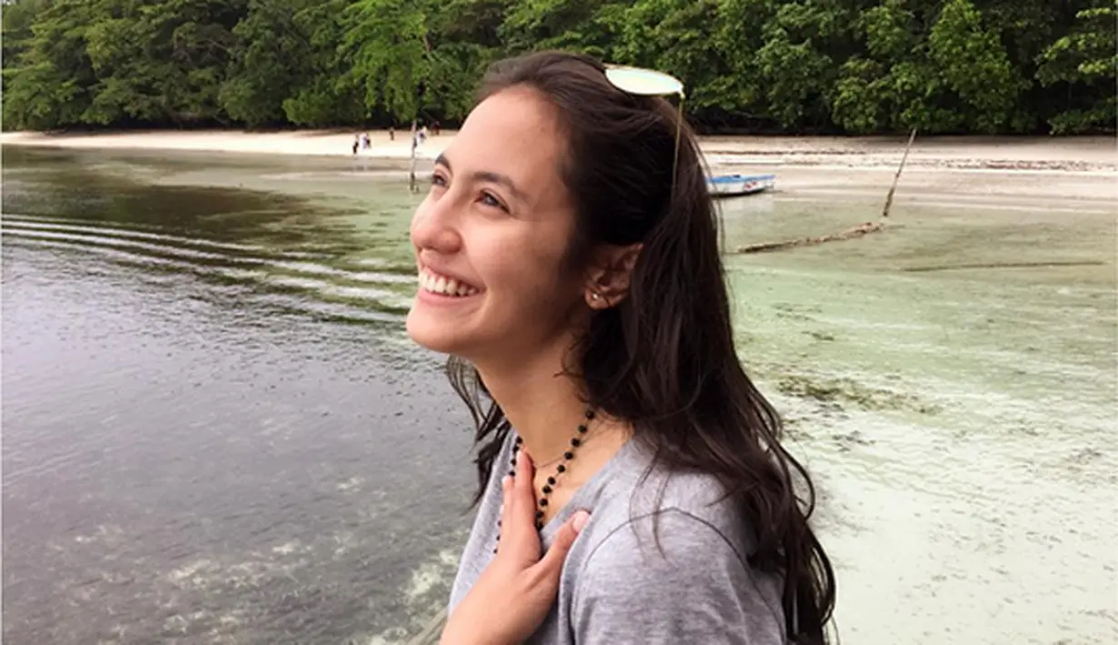 Duduk dipinggir pantai dengan raut wajah begitu ceria. Rambut dibiarkan terurai.  (Bintang.com/@pevpearce)