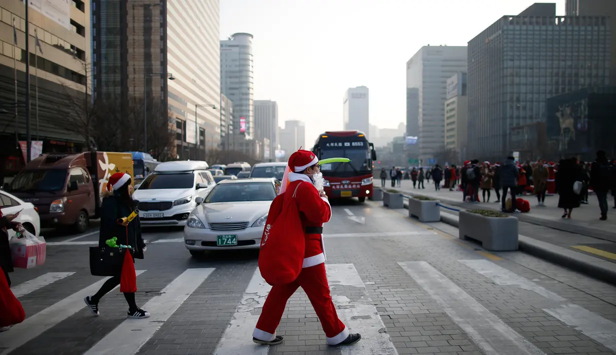 Seorang pria berpakaian seperti Santa Claus berjalan di zebra cross selama acara amal Natal di pusat kota Seoul, Korea Selatan, (24/12/2015). (REUTERS/Kim Hong-Ji)