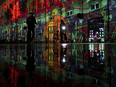 Orang-orang melewati pertunjukan cahaya malam di Lyon, Prancis tengah, Rabu (8/12/2021). Jutaan orang diperkirakan akan menghadiri acara Festival of Lights selama empat hari di kota itu. (AP Photo/Laurent Cipriani)