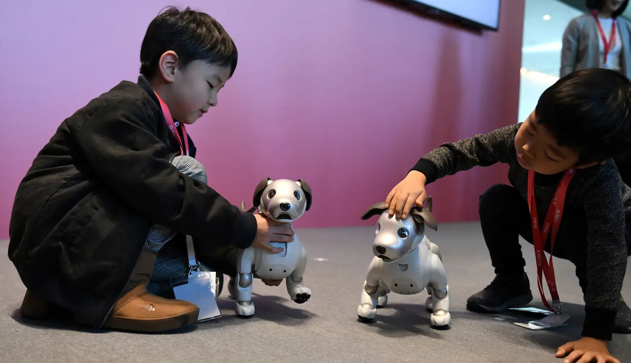 Dua orang anak bermain dengan robot anjing dari Sony, Aibo setelah setelah upacara ulang tahun sekaligus peresmiannya di Tokyo, Jepang (11/1). (AFP Photo/Kazuhiro Nogi)