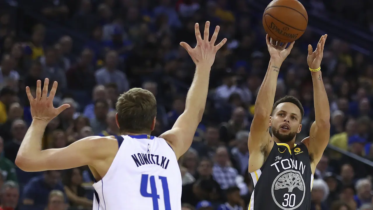 Stephen Curry (hitam) melepaskan tembakan saat Warriors menghajar Mavericks