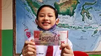 Muhammad Izzam Athaya memamerkan uang kertas pecahan baru yang berisi foto dirinya mengenakan pakaian adat Suku Tidung. (Foto: Siti Hardiani)