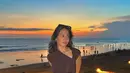 Menikmati matahari tenggelam di pantai, Pevita Pearce tampil cantik mengenakan atasan cropped top cokelat dengan bahu asimetris dan rok panjangnya yang serasi. [Foto: Instagram/pevpearce]