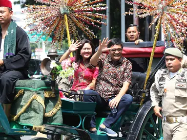 Gubernur DKI Jakarta Djarot Saiful Hidayat bersama istri Happy Farida menaiki delman sambil melambaikan tangan kepada warga dan pegawai Pemprov DKI Jakarta saat perpisahan dirinya di Balaikota DKI Jakarta, Minggu (15/10). (Liputan6.com/Immanuel Antonius)