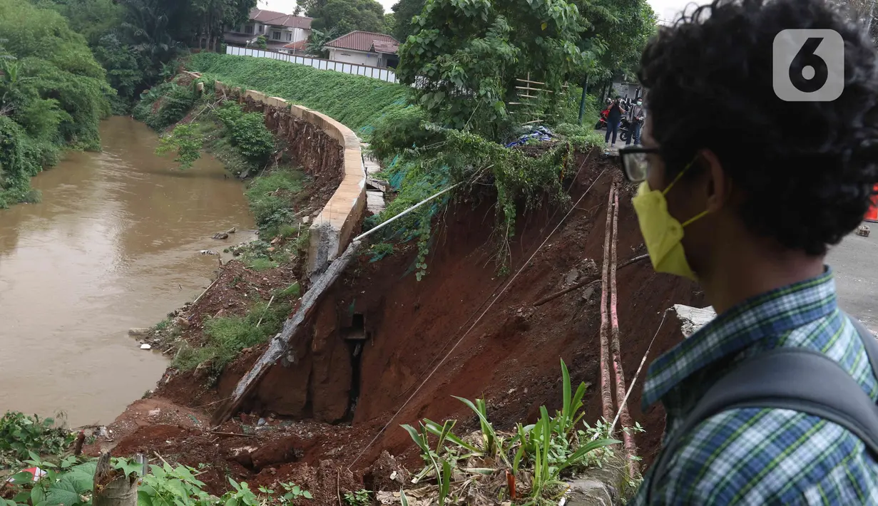 Warga melihat Lokasi longsor di daerah bantaran sungai Ciliwung, Pengadegan Timur, Jakarta, Selasa (12/4/2022). Longsor sepanjang 25 meter, lebar lima meter, dan kedalaman 15 meter itu menyebabkan 4 sepeda motor tertimbun material longsor, namun tidak ada korban jiwa. (Liputan6.com/Herman Zakharia)