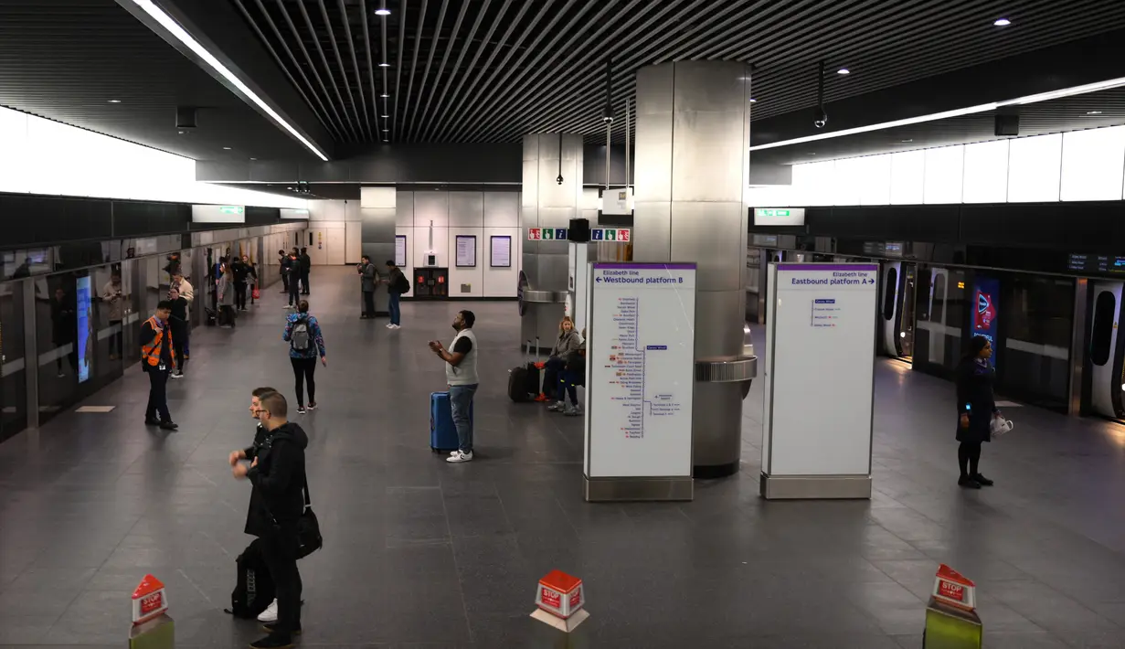 Para penumpang menunggu di Stasiun Canary Wharf Elizabeth Line yang baru dibuka di London Timur, Inggris, Senin (7/11/2022). Dalam peluncuran layanan terbaru ini penumpang yang mendarat di Bandara Heathrow akan dapat mencapai tujuan seperti Farringdon dalam waktu sekitar 40 menit atau Canary Wharf dalam waktu sekitar 50 menit. (Daniel LEAL / AFP)