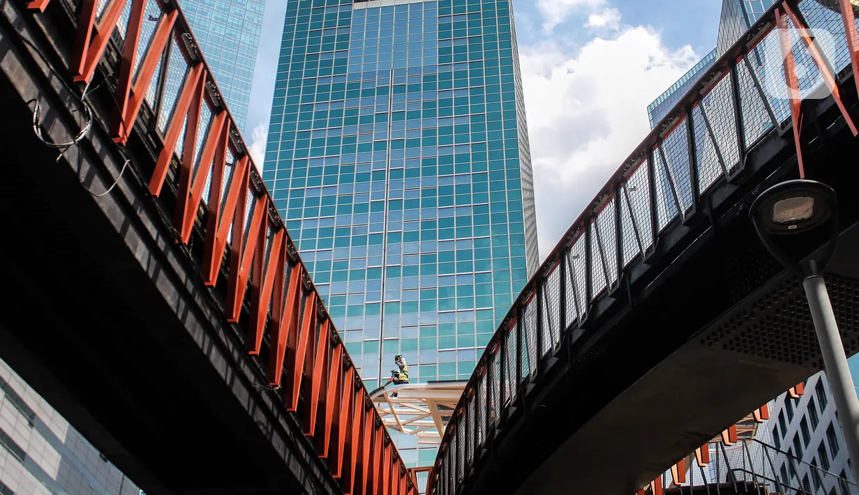 Aktivitas pengerjaan revitalisasi Jembatan Penyeberangan Orang (JPO) di Jalan Sudirman, Jakarta, Minggu (19/12/2021). JPO yang juga dilengkapi Anjungan Pandang Jakarta dan terintegrasi halte TransJakarta ini telah mencapai 95 persen dan akan dapat diakses pada akhir 2021. (Liputan6.com/JohanTallo)