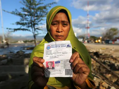 Seorang ibu bernama Lita, menunjukkan foto anaknya, Nanang Kosim (20) yang belum ditemukan pascagempa dan tsunami Palu di Pantai Talise, Sulawesi Tengah, Senin (8/10). Nanang diduga masih tertimbun di dalam tanah saat tsunami. (Liputan6.com/Fery Pradolo)