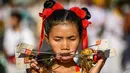 Seorang wanita menusuk pipinya dengan besi  saat mengikuti prosesi perayaan Festival Vegetarian tahunan di Phuket, Thailand, Kamis (3/10/2019). Festival dimulai pada malam pertama bulan lunar kesembilan dan berlangsung selama sembilan hari. (AFP Photo/Mladen Antonov)