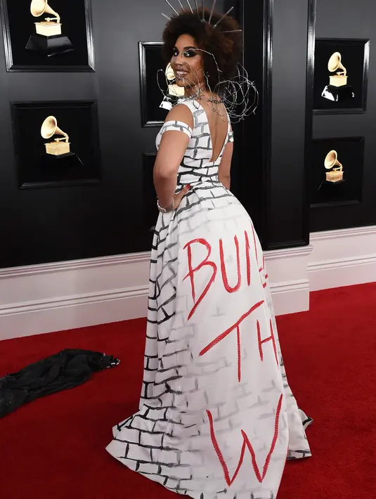 Penyanyi dan komposer, Joy Villa mengenakan gaun bertuliskan "Build the Wall" pada perhelatan Grammy Awards 2019 di Los Angeles, Minggu (10/2). Detail kawat di bagian pundak menambah kesan tembok perbatasan antara AS-Meksiko. (Jordan Strauss/Invision/AP)