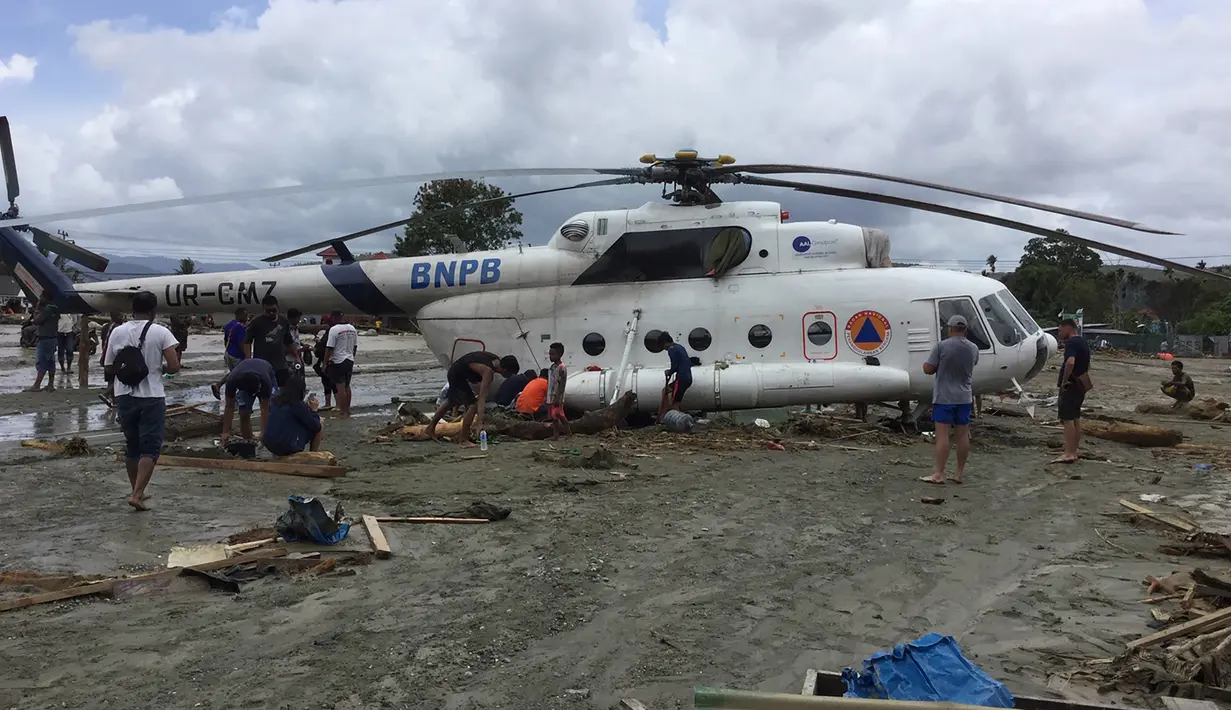 Warga berusaha menggali lumpur yang menimbun helikopter Mi-17 milik BNPB pasca banjir bandang di Kabupaten Sentani, Jayapura, (17/3). Banjir bandang Sentani menewaskan 70 orang dan puluhan luka-luka. (AFP/Netty Dharma Somba)