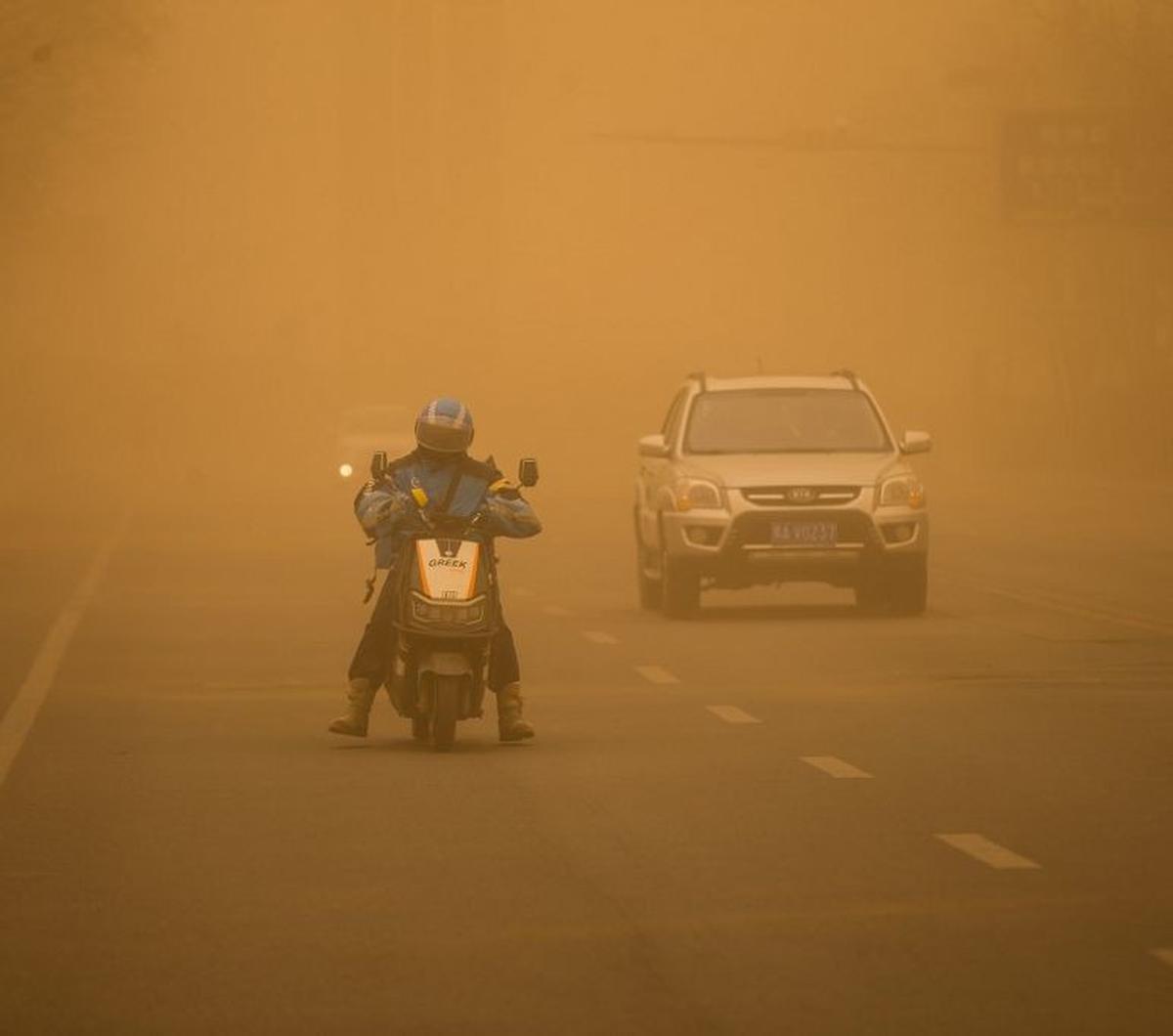 Seorang pengendara motor tampak berhati-hati ketika berkendara di tengah badai pasir yang menerjang Kota Jilin, Provinsi Jilin, China, pada 28 Maret 2024. Terpaan badai pasir parah yang melanda China ini disebabkan oleh cuaca dingin dan angin kencang.&nbs