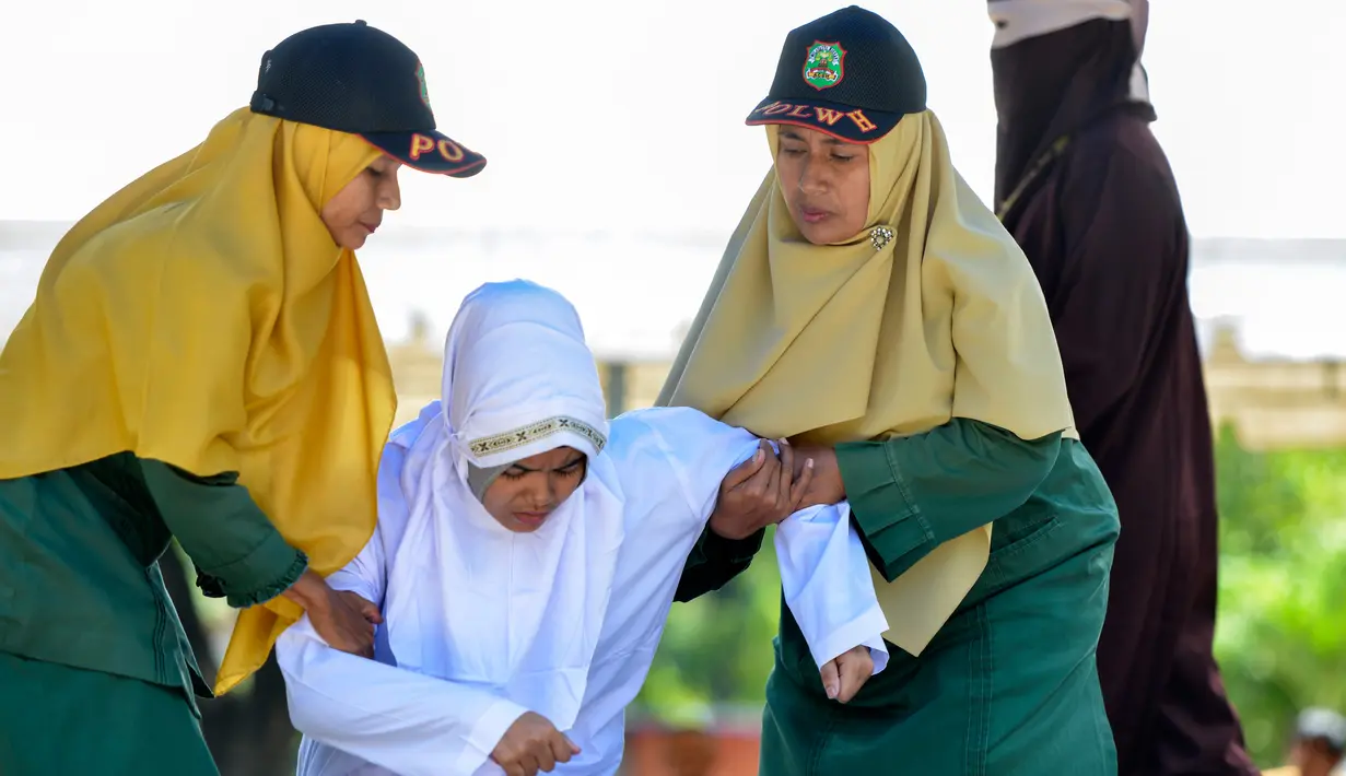 Polisi syariah membawa Nur Fadilah (21) usai dihukum cambuk karena mesum di Banda Aceh, Senin (29/10). Ikhtilat adalah perbuatan bermesraan antara laki-laki dan perempuan yang bukan suami istri dengan kerelaan kedua belah pihak. (Chaideer Mahyuddin/AFP)