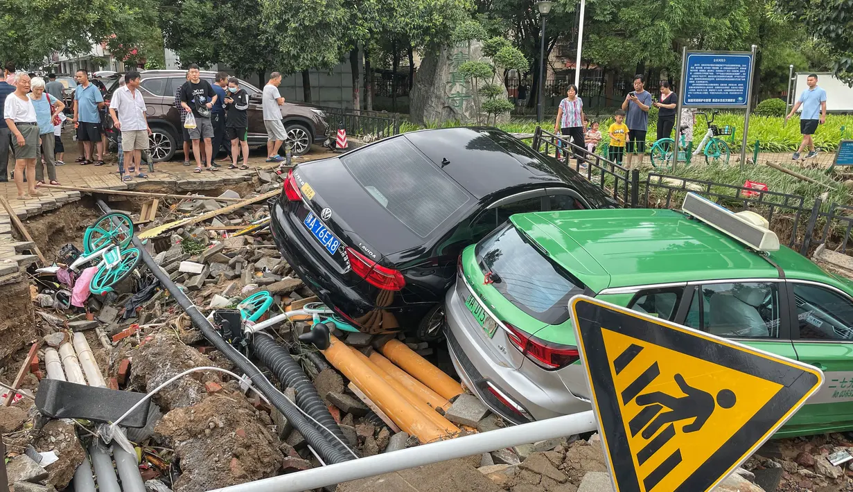 Mobil-mobil yang rusak bertumpuk pada puing-puing setelah hujan lebat melanda kota Zhengzhou yang menyebabkan banjir di provinsi Henan, China tengah (21/7/2021). Luapan sungai menggenangi jalan-jalan dan membuat kendaraan terbawa arus setelah curah hujan 200 mm turun dalam satu jam. (AFP/STR)