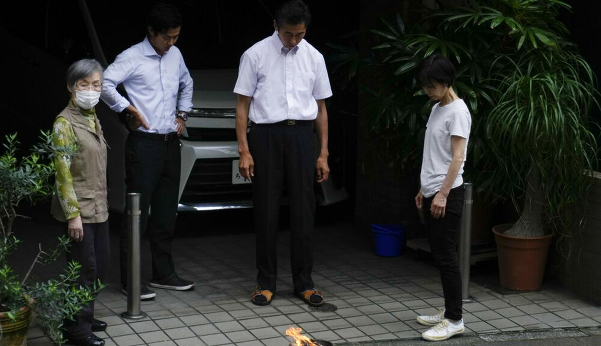 Satu keluarga melihat api kecil yang menyala di luar rumah mereka untuk menghormati leluhur di Tokyo, Jepang, Selasa (13/7/2021). Keadaan darurat akan berlaku sepanjang Olimpiade yang dibuka pada 23 Juli. (AP Photo/Jae C. Hong)