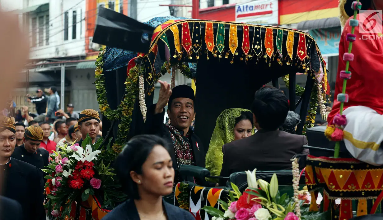 Presiden Joko Widodo bersama Ibu Negara Iriana saat membagikan kaus di atas kereta kencana saat kirab resepsi pernikahan Kahiyang Ayu-Bobby Nasution di Kota Medan, Sumatera Utara, Minggu (26/11). (Liputan6.com/Johan Tallo)