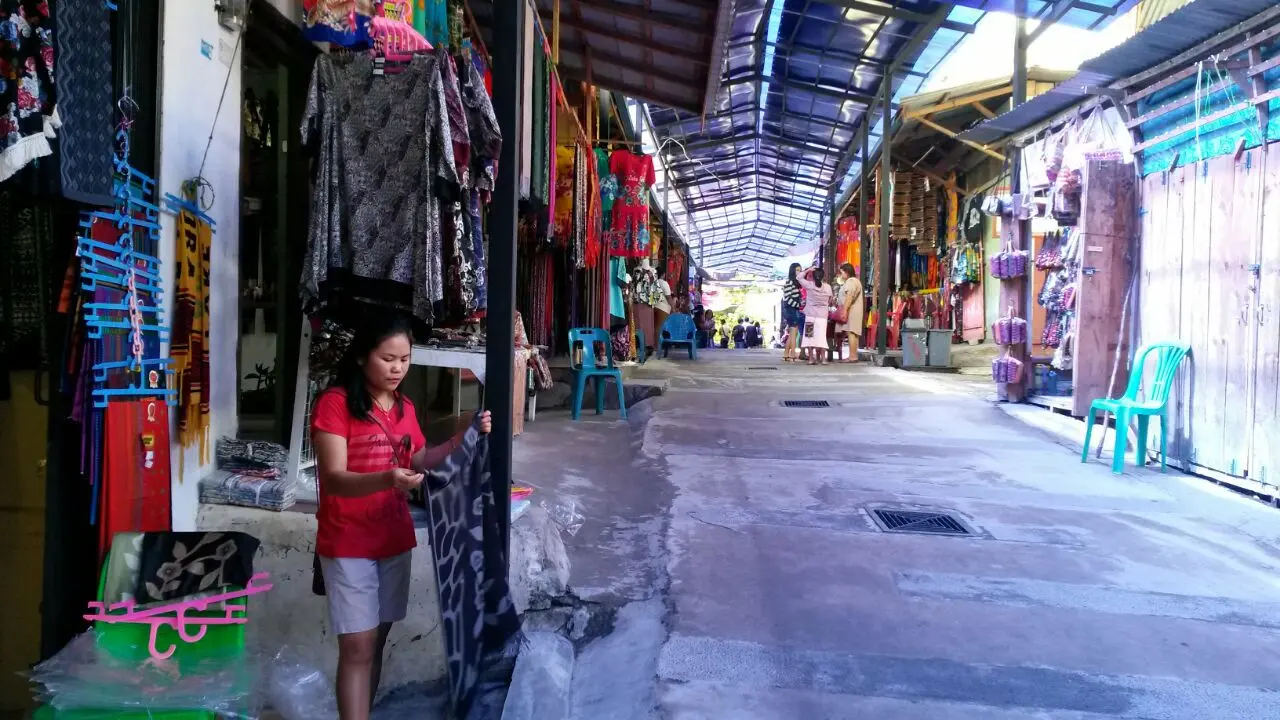 Sukarela Situmorang (kaus merah) di pasar cinderamata di Desa Tomok, Pulau Samosir, Danau Toba (Rizki Akbar Hasan/Liputan6.com)