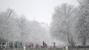 Orang-orang berjalan saat salju turun di Taman Retiro di pusat kota Madrid (7/1/2021). Sistem tekanan rendah bergerak ke timur laut dari Madeira di Atlantik, membawa massa udara yang sangat dingin ke Spanyol. (AFP/Gabriel Bouys)