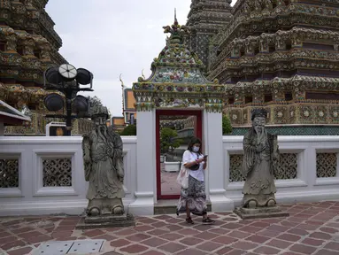 Turis yang mengenakan masker berjalan-jalan di kuil Wat Pho di Bangkok, Thailand, pada 23 Februari 2022. Thailand akan melonggarkan beberapa persyaratan masuk bagi turis asing untuk membangun kembali yang rusak akibat pandemi ekonomi. (AP Photo/Sakchai Lalit)