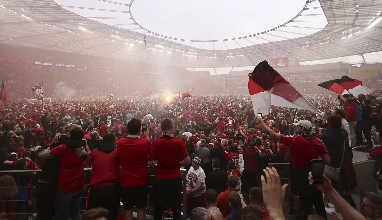 Suporter Bayer Leverkusen memadati lapangan pertandingan untuk merayakan keberhasilan timnya memastikan gelar juara Liga Jerman 2023/2024 setelah mengalahkan Werder Bremen di BayArena, Leverkusen, Jerman, Senin (15/04/2024) WIB. (AP Photo/DPA/Rolf Vennenbernd)