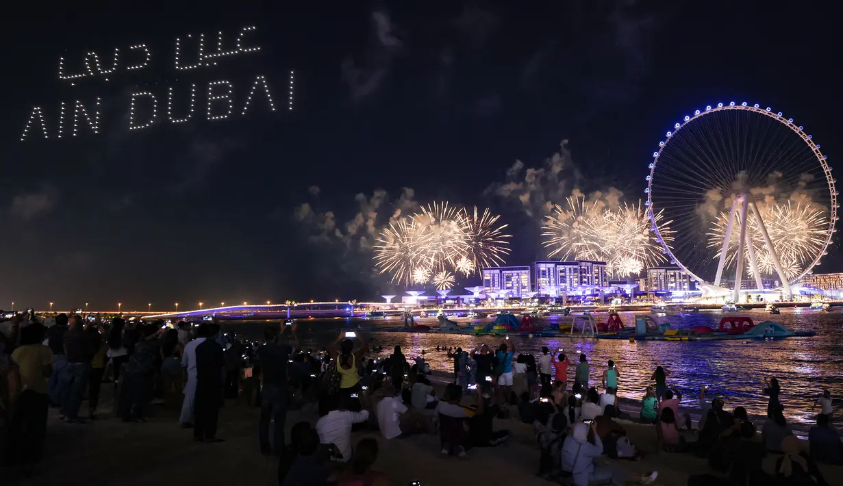 Kembang api menerangi langit selama upacara pembukaan Dubai Eye, yang dikenal sebagai Ain Dubai, di kota Emirat, dekat Dubai Marina, Kamis (21/10/2021). Bianglala terbesar dan tertinggi di dunia tersebut resmi dibuka untuk umum. (Giuseppe CACACE / AFP)