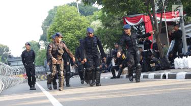 Personel Brimob menari bersama disela-sela berjaga di depan Gedung Mahkamah Konstitusi (MK), Jakarta, Selasa (25/6/2019). Jelang sidang pembacaan putusan akan digelar pada Kamis (27/6), penjagaan di sekitar Gedung Mahkamah Konstitusi diperketat. (Liputan6.com/Helmi Fithriansyah)