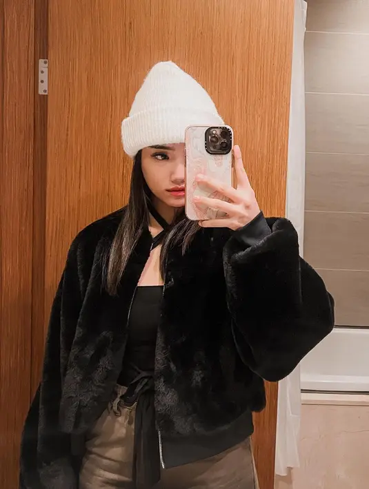 Fuji memadukan tank top dengan detail cross-neck berwarna hitam dengan jaket bulu yang juga berwarna hitam, dipadukannya dengan celana berwarna cokelat. Fuji memadukan keseluruhan penampilannya dengan bucket hat putih. [Foto: Instagram/fuji_an]