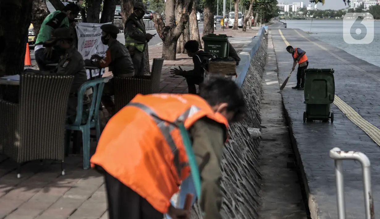 Warga menjalani sanksi menyapu jalanan sambil mengenakan rompi pelanggar PSBB saat Operasi Tertib Masker (Tibmask) di kawasan Sunter, Jakarta, Kamis (3/9/2020). Sanksi denda pelanggaran tidak menggunakan masker mencapai Rp2,1 Miliar di Ibu Kota. (merdeka.com/Iqbal Nugroho)