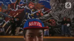 Seorang anak mengenakan topi Marvel berdiri dengan latar belakang mural kolaborasi di Terowongan Kendal, Kawasan TOD Dukuh Atas, Jakarta, Rabu (6/7/2022). Karya seni mural yang terinspirasi dari film Marvel Studios "Thor: Love and Thunder" itu memanfaatkan teknologi augmented reality (AR). (Liputan6.com/Faizal Fanani)