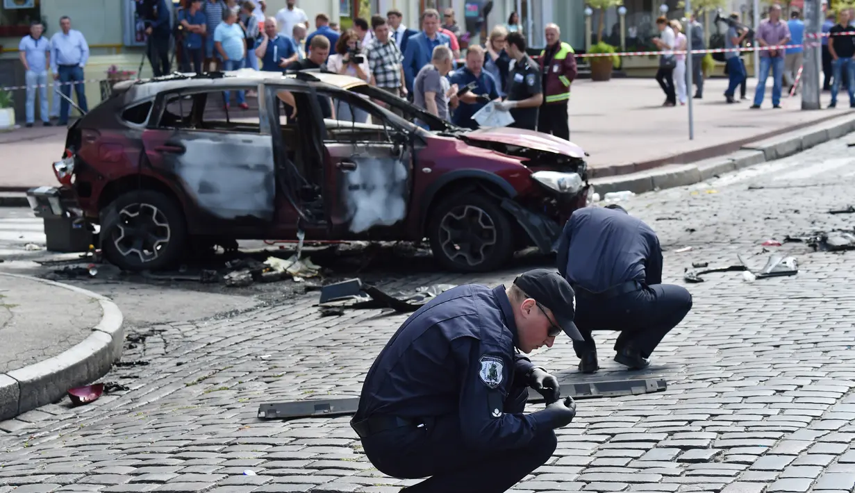 Petugas ahli forensik Ukraina memeriksa lokasi tewasnya jurnalis investigasi ternama, Pavel Sheremet di Kiev, Rabu (20/7). Jurnalis Ukrayina Pravda itu sedang mengendarai mobil ke tempat kerja ketika mobil tersebut meledak. (Sergei SUPINSKY/AFP)
