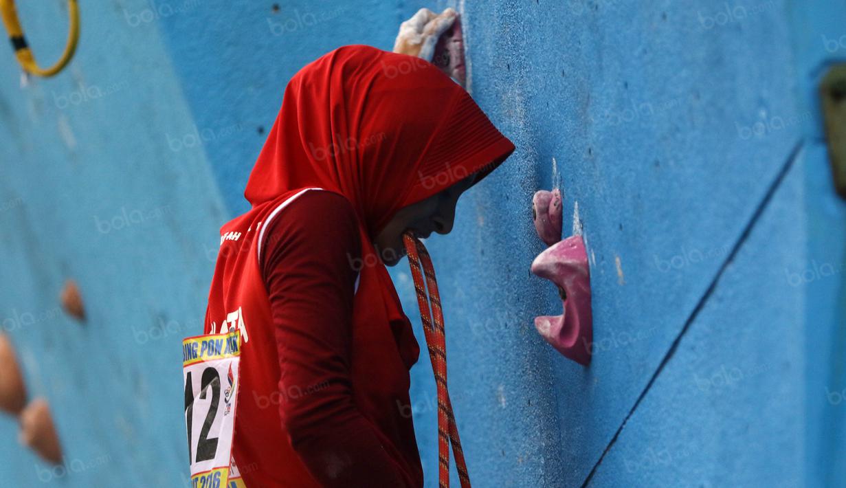 Atlet Panjat Tebing DKI Jakarta, Syarifah mengigit tali karmantel saat memanjat pada kategori Lead Cabang Panjat Tebing PON XIX Jabar 2016 di Cikole, Bandung. (Bola.com/NIcklas Hanoatubun)
