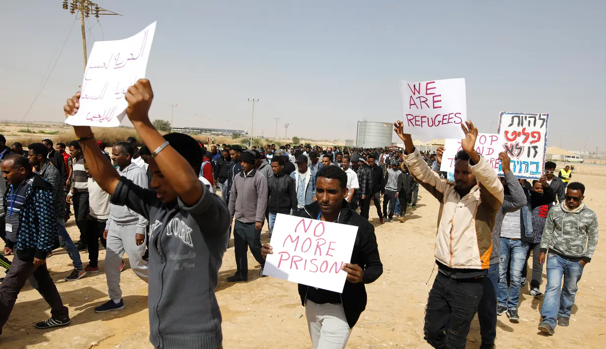 Migran Afrika berkumpul berjalan menuju Penjara Saharonim untuk melakukan aksi di gurun selatan Negev, Israel (22/2). Mereka melakukan aksi protes terkait sembilan orang dari migran Afrika yang dipenjara oleh Israel. (AFP Photo/Menahem Kahana)