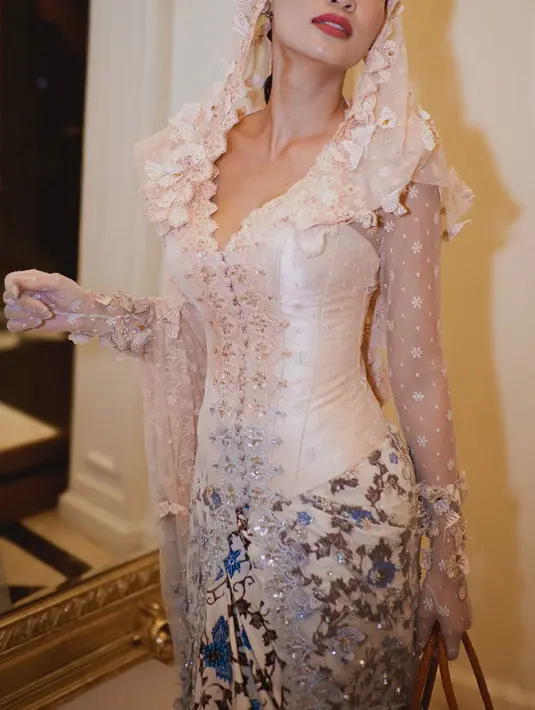 Yang membuat penampilan ini makin teatrikal adalah veil panjang yang menghiasi kepalanya, terbuat dari tulle transparan dengan motif polkadot halus dan hiasan renda, menciptakan kesan agung dan penuh kelembutan sekaligus. [@patriciagouw].