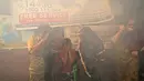 Sebuah keluarga berjalan melewati asap dari fogging di daerah padat penduduk di New Delhi, India, Rabu (27/10/2021). New Delhi telah melaporkan ratusan kasus demam berdarah, dengan lebih dari 200 kasus baru dalam seminggu terakhir, menurut laporan yang dirilis pada Senin. (AP Photo/Manish Swarup)